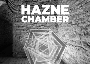 Taş duvarlı bir odada, yere yerleştirilmiş geometrik bir ışık enstalasyonu bulunuyor. Üst kısımda beyaz harflerle 'HAZNE CHAMBER' yazısı yazıyor. Görsel siyah beyaz tonlarda.
