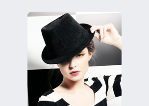 Siyah beyaz zemin önünde, 20’lerinde bir kadın siyah bir fötr şapka takmış, bir eliyle şapkasının kenarını tutuyor, beyaz üzerine siyah çizgili bir üst giymiş, dudakları açık pembe tonlarında.