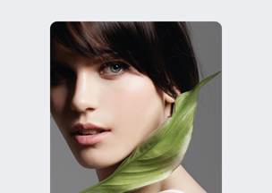 Gri arka plan önünde, 20’lerinde bir kadın omzuna doğru uzanan büyük yeşil bir yaprakla birlikte kadrajda yer alıyor, kısa koyu kahverengi saçları ve açık teniyle sade bir portre oluşturulmuş.