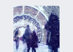 Işıklarla kaplı bir tünel boyunca yürüyen insanlar var, tünelin tavanı yıldız biçiminde parlayan küçük ampullerle dolu, zemin karla kaplı.